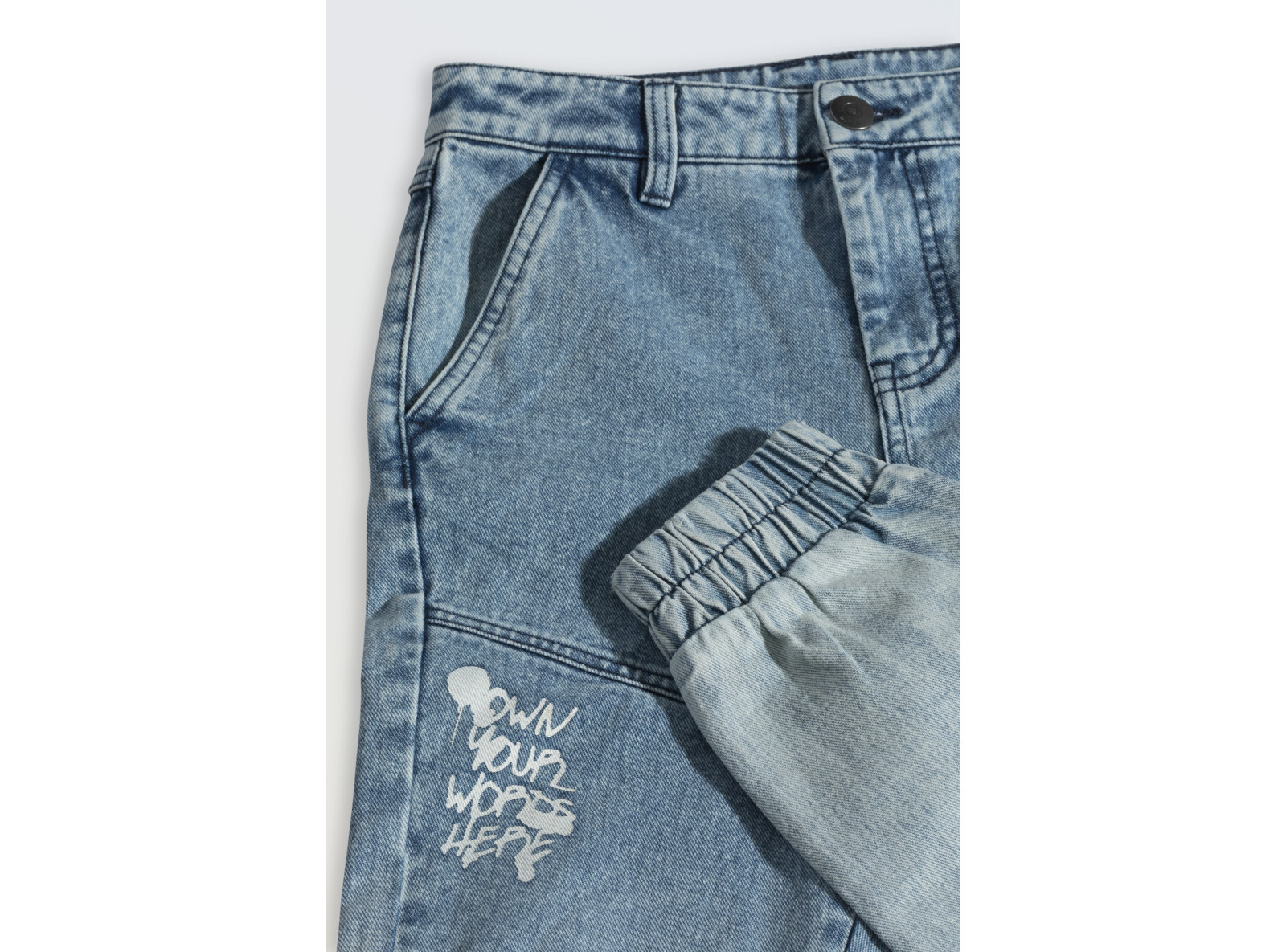 Niebieskie spodnie jeansowe typu joggery z nadrukami na nogawkach